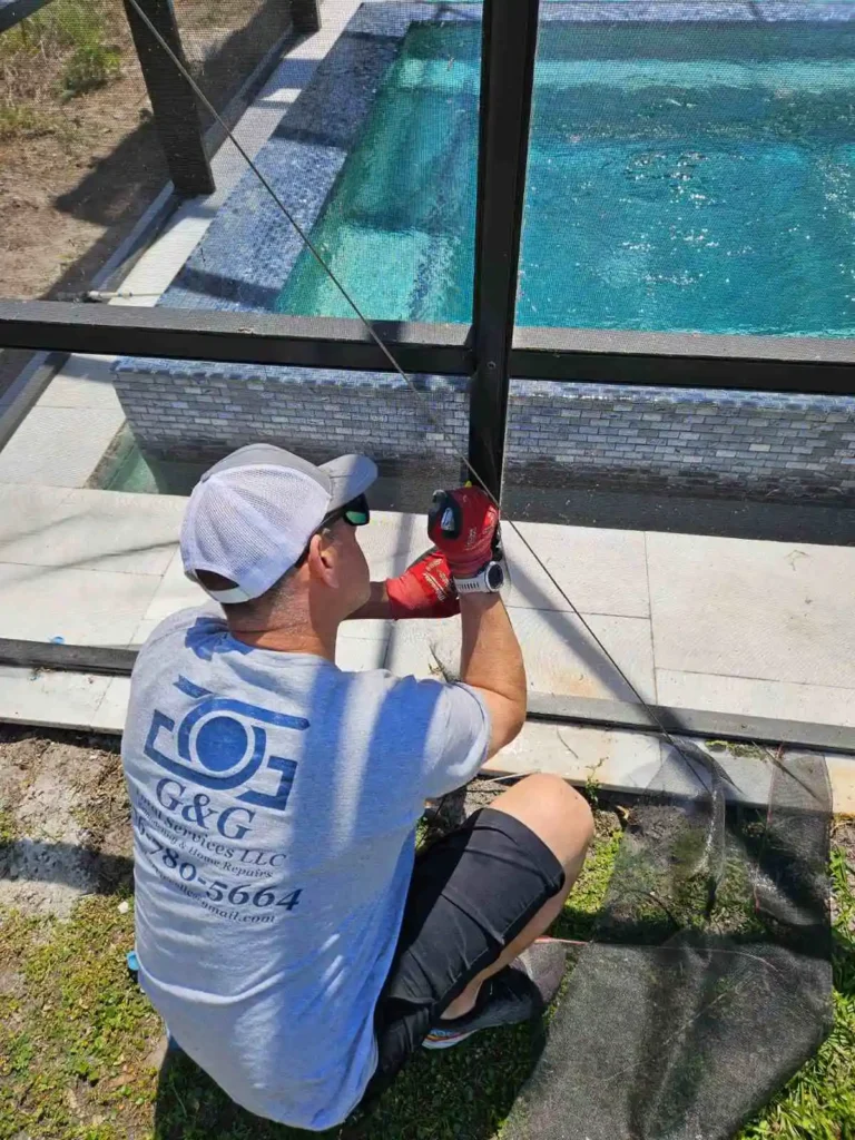 Technician repairing pool enclosure screen with power drill in St. Cloud, Florida